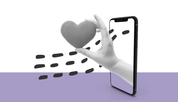 Uma mão que segura um coração sai da tela de um smartphone.