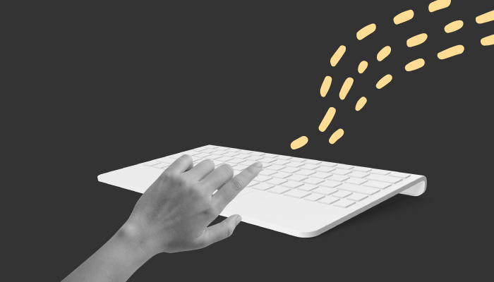 Uma mão digita algo em um teclado.