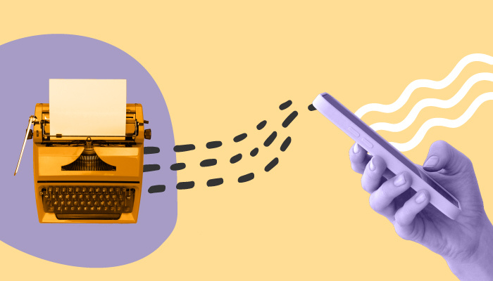 Uma máquina de escrever ao lado de uma mão segurando um smartphone.
