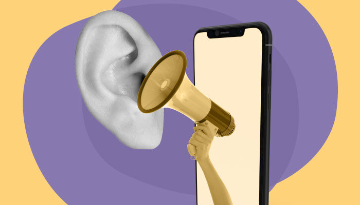 Imagem abstrata: uma mão com um megafone sai de uma tela de celular e se posiciona próxima a uma orelha.