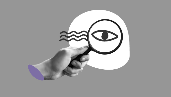 Imagem mostra mão segurando uma lupa com um desenho de olho dentro