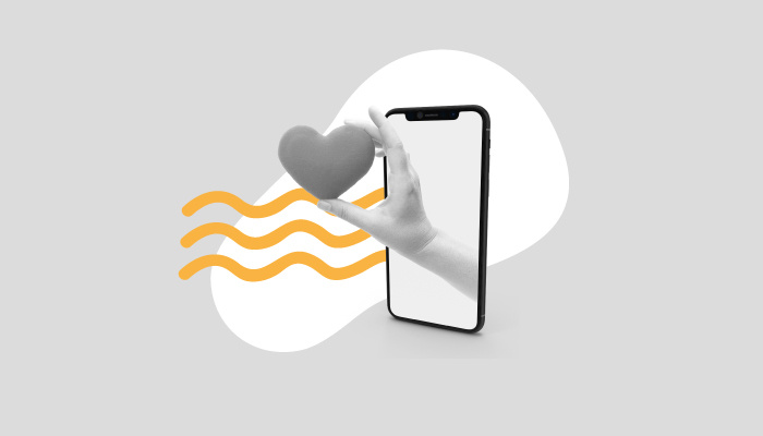 Uma mão segurando um coração sai de um smartphone.