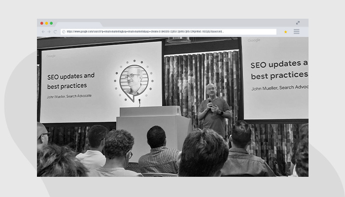 Foto em preto e branco mostra John Mueller, líder da equipe de Search Relations no Google, em palestra no evento Search Central Live